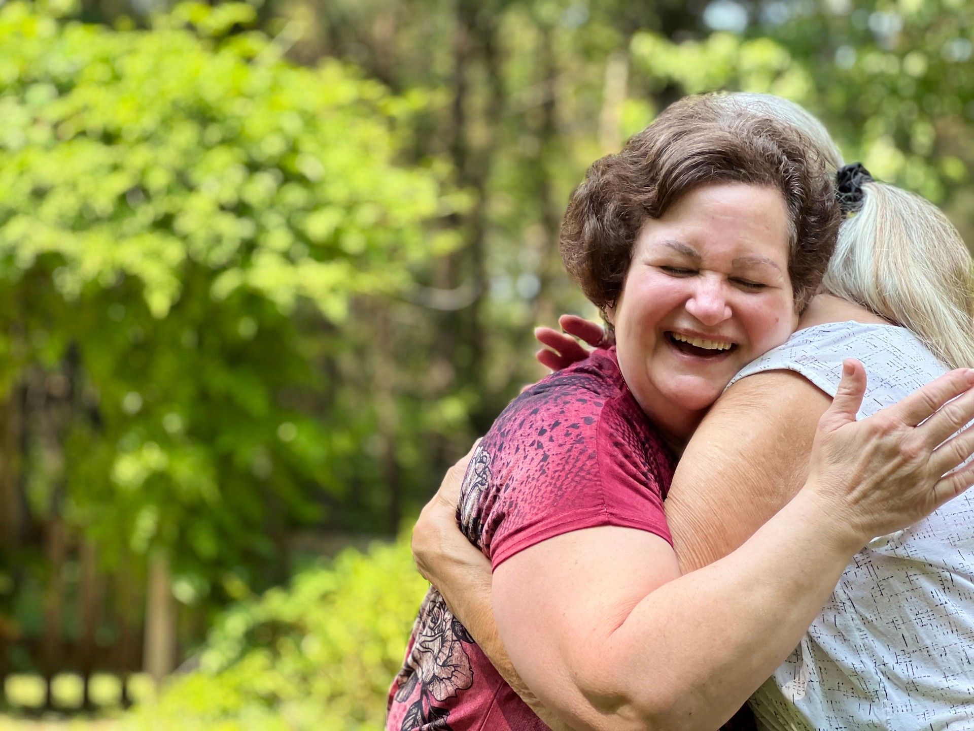 Two senior women friends hug as they meet up after the pandemic